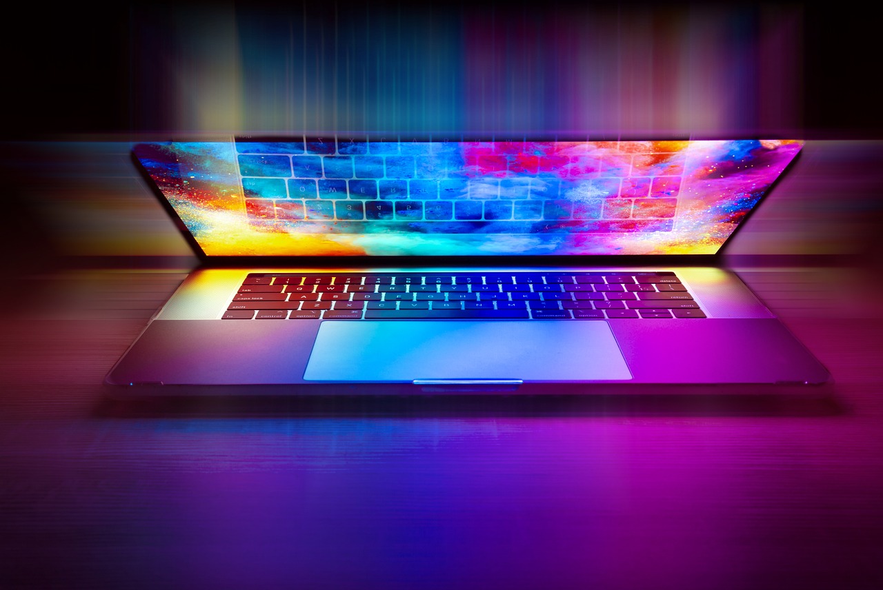 Geöffneter Laptop mit buntem Bildschirm und Tastatur auf einem Tisch.